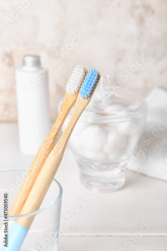 Glass with wooden toothbrushes on white wooden table, closeup