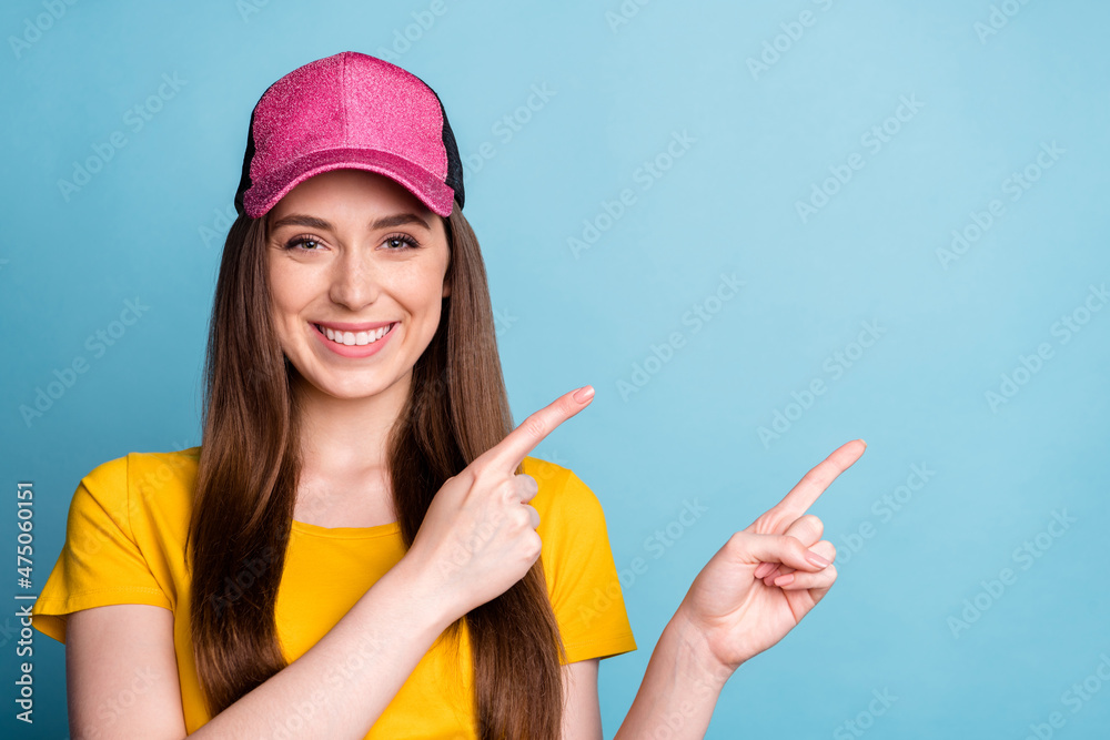 Photo of cute lady direct index fingers empty space wear pink cap yellow t-shirt isolated blue color background Photo of cute lady direct index fingers empty space wear pink cap yellow t-shirt isolated blue color background