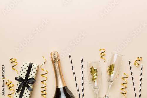 Champagne bottle, glitter and straws on color background. top view. Hilarious, christmas and birthday celebration