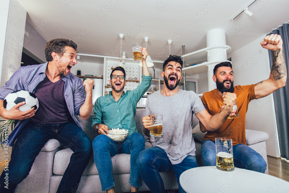Very excited friends having fun by watching football match at home, indoors. Friendship, leasure,sport, rest, home party concept Very excited friends having fun by watching football match at home, indoors. Friendship, leasure,sport, rest, home party concept