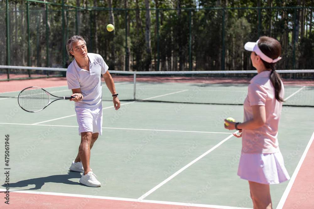 Happy mature couple playing tennis outdoors