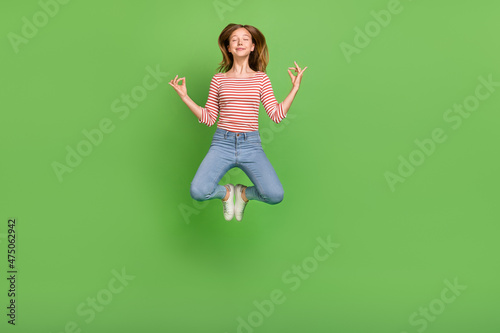 Photo of peaceful serene calm lady jump enjoy meditation practice wear striped shirt isolated green color background