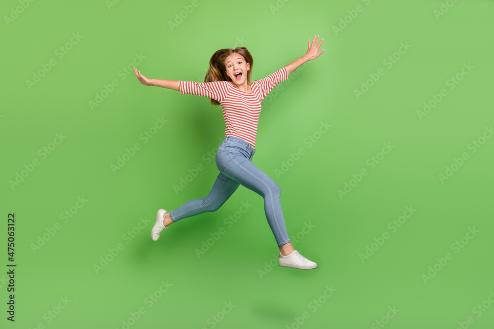 Photo of excited crazy inspired lady jump run have fun raise hands wear striped shirt isolated green color background