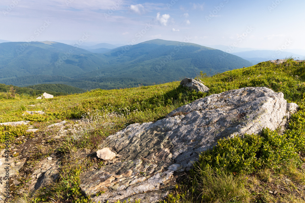 summer mountain landscape. stones on the grassy hill. beautiful nature background in a sunny morning. clouds on the sky. outdoor travel scenery summer mountain landscape. stones on the grassy hill. beautiful nature background in a sunny morning. clouds on the sky. outdoor travel scenery