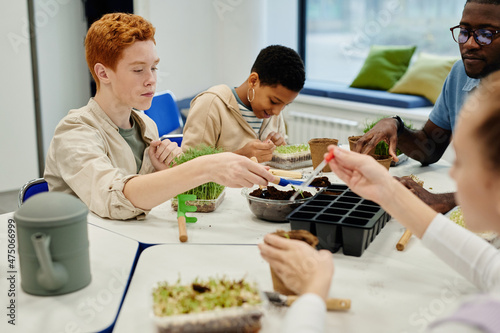 Diverse group of children planting seeds while experimenting during biology class in school