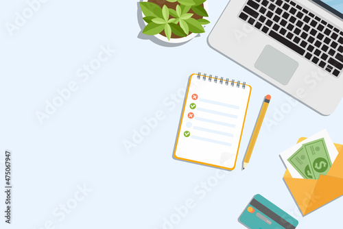 Flat lay minimal office workspace. 
A laptop with a notepad, a bank card and an envelope with money.