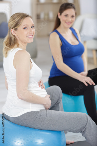 two pregnant women sitting on exercise balls in gym