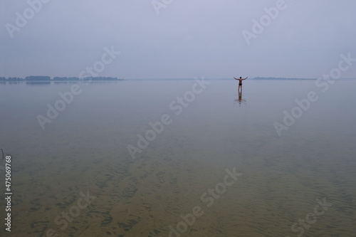 Blurred image of Lake Svityaz, Ukraine on a foggy morning. In the distance a silhouette of a happy lonely man. Copy space. 