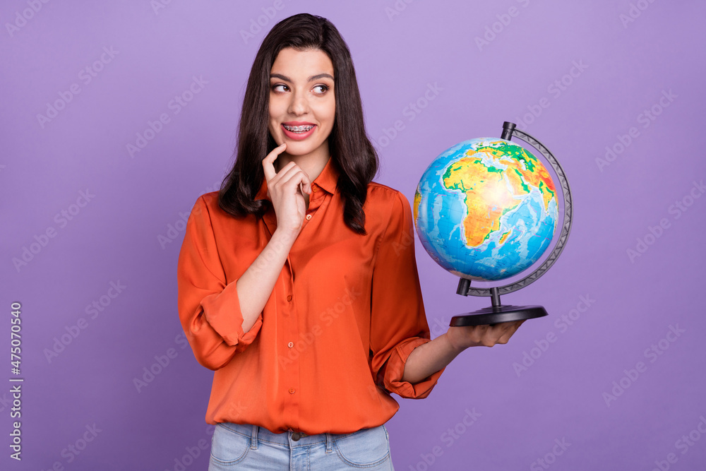 Fototapeta premium Portrait of attractive minded cheerful girl holding exploring globe thinking isolated over bright purple violet color background