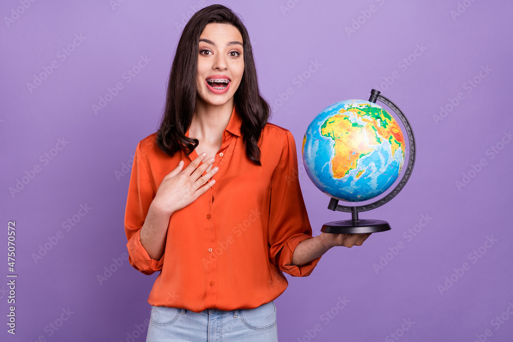 Fototapeta premium Portrait of attractive impressed cheerful girl holding studying globe isolated over bright purple violet color background