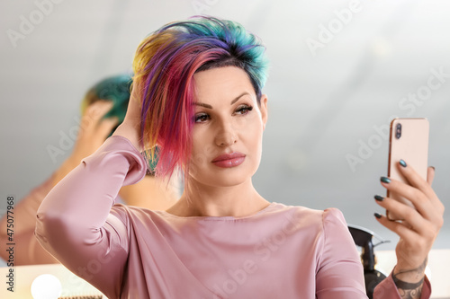 Woman with unusual hair color taking selfie in beauty salon
