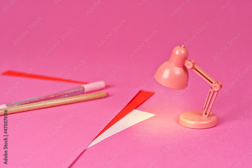 Pink lamp on a background of papers. Toy table lamp. Copy space and free space for text near the lamp. The concept of roochy space and creative ideas. Pink lamp on a background of papers. Toy table lamp. Copy space and free space for text near the lamp. The concept of roochy space and creative ideas.