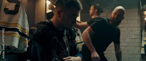 Teammates cheering up disappointed ice hockey player in the locker room after the game. Shoot with 2x anamorphic lens