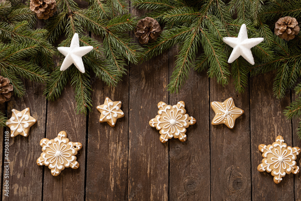 Star and snow flake shaped Christmas ginger cookies with glazed icing decoration placed on conifer and wooden background Star and snow flake shaped Christmas ginger cookies with glazed icing decoration placed on conifer and wooden background