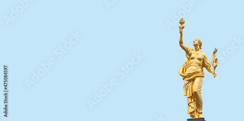 Banner with a golden statue of Greek goddess of peace Eirene, Pax, with heart and laurel branch in her hands, symbols of love and peace, at blue sky solid background with copy space. photo