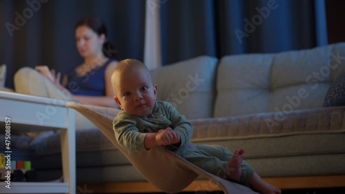 Wallpaper Mural Mother with child in the living room in the evening, mom uses a smartphone, baby boy is watching tv. High quality 4k footage Torontodigital.ca