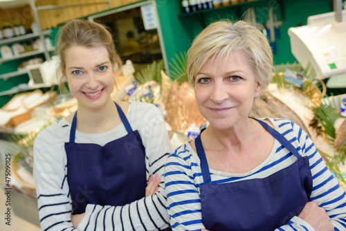 cute salesgirl and woman offers the buyer a fresh fish