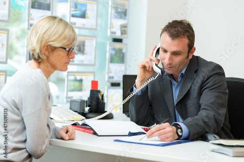 estate agent in office with client talking on landline
