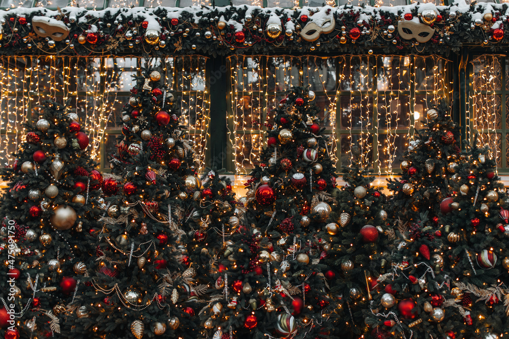 festive Christmas tree with red golden shiny Christmas balls and garlands on the street in the winter season. Magic atmosphere festive Christmas tree with red golden shiny Christmas balls and garlands on the street in the winter season. Magic atmosphere