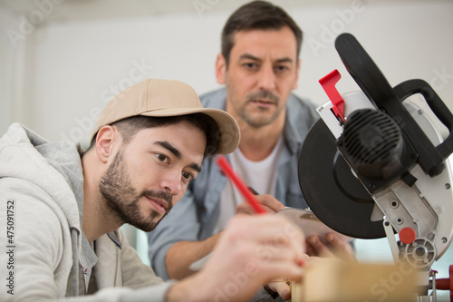 supervisor assessing apprentice to use circular saw