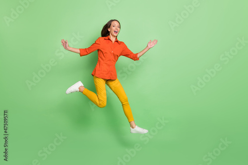 Full length photo of young lovely excited lady have fun jump fly isolated over green color background