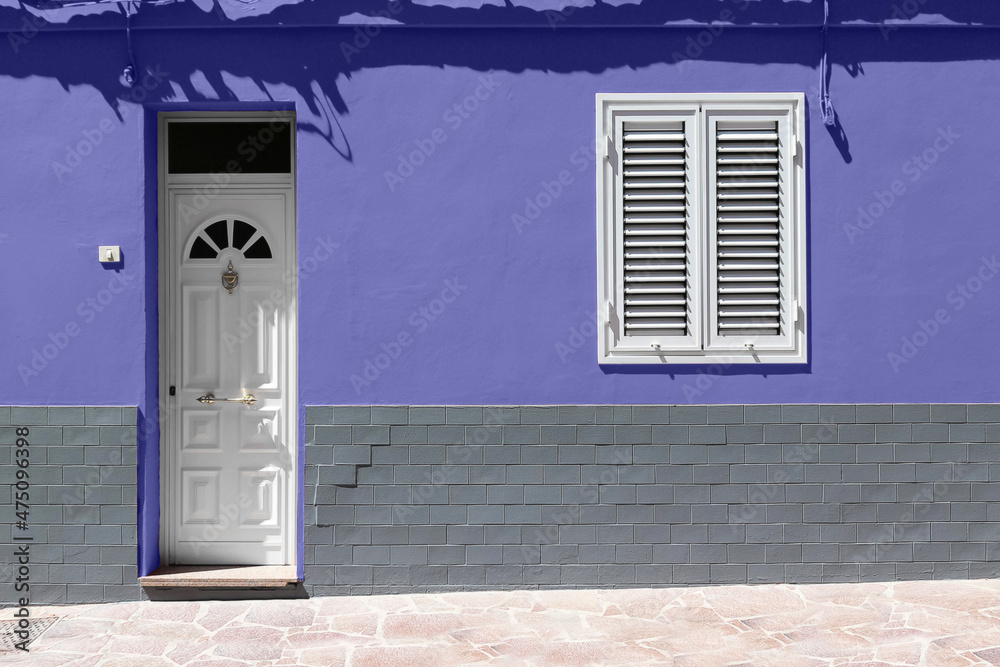 White wooden front door and white window on very peri wall with gray brick. Color trend of the year.