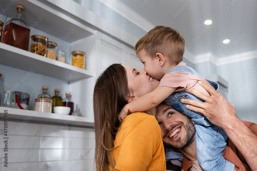 Smiling woman kissing son near husband at home Smiling woman kissing son near husband at home