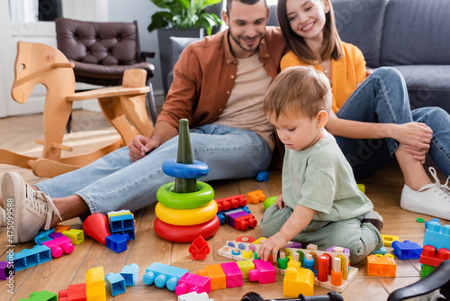 Toddler kid playing educational game near parents and rocking horse at home