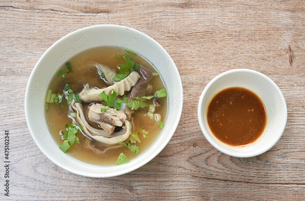 boiled slice pork stomach and bone soup in bowl dipping spicy sauce cup on table boiled slice pork stomach and bone soup in bowl dipping spicy sauce cup on table