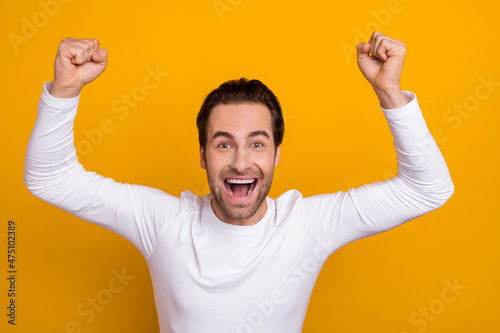Photo of overjoyed delighted guy raise fists lucky scream hooray yes isolated on yellow color background