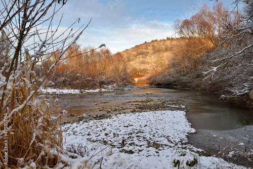 Winter landscape with a mountain river. Beautiful sunset. First snow this year.