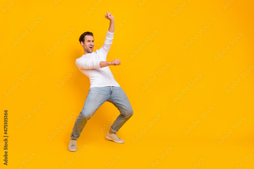 Full size photo of cool brunet young guy ride hourse wear white shirt jeans sneakers isolated on yellow color background