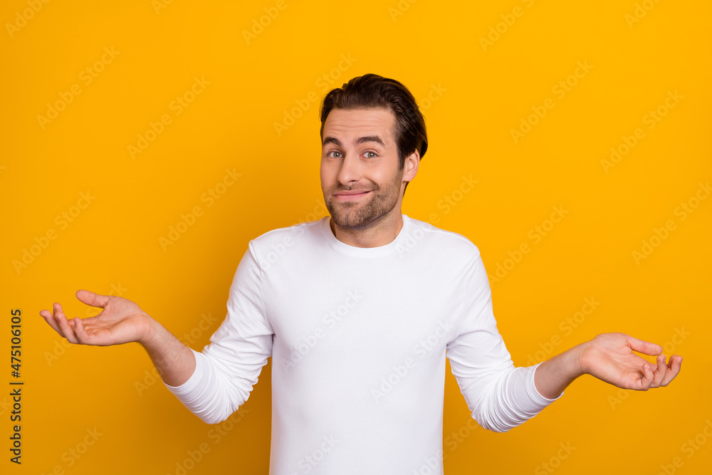 Photo of millennial unsure brunet guy shrug shoulders wear white shirt isolated on bright yellow color background