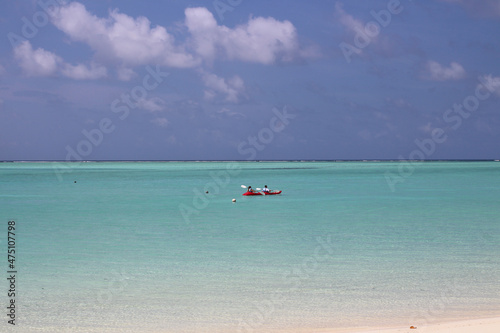 Fototapeta Naklejka Na Ścianę i Meble -  Morning in the Maldives, a man and a woman are sailing on a kayak along the coast of the Indian Ocean with white sand, corals in azure water