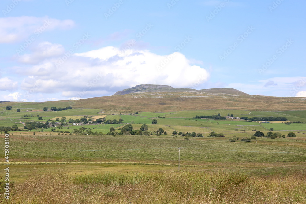 The famous peak of Ingleborough in the Yorkshire Dales National Park surrounded by lush grassland.