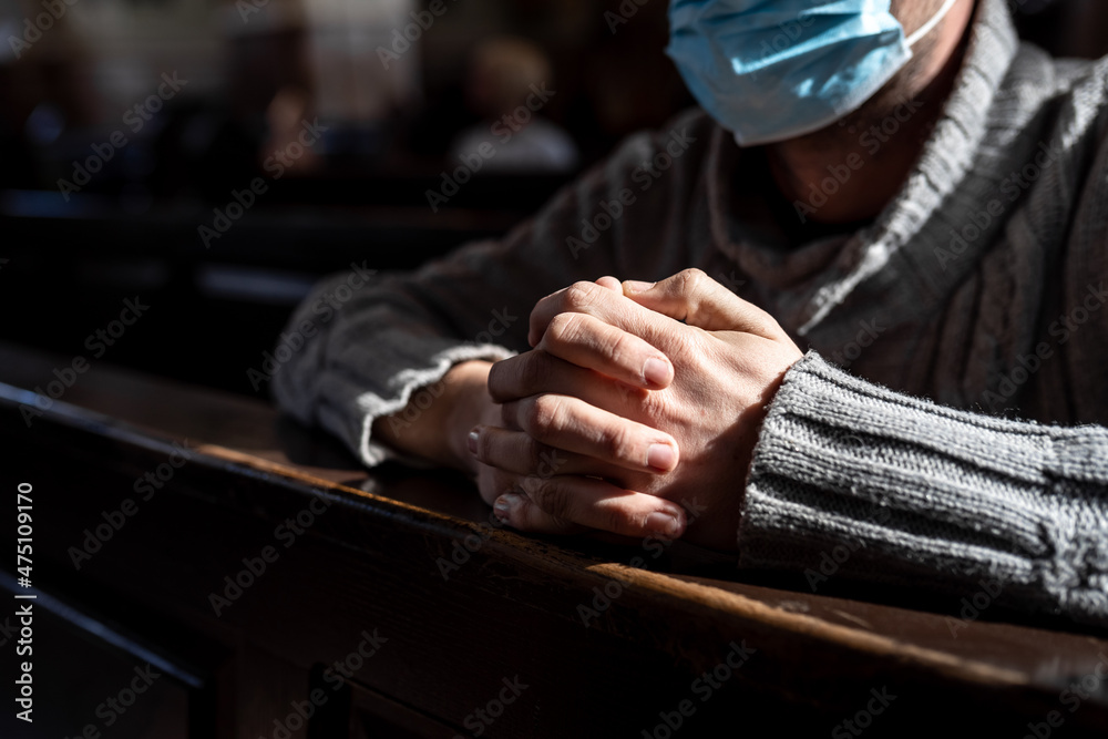 Masked man is praying in the church. Hands close up