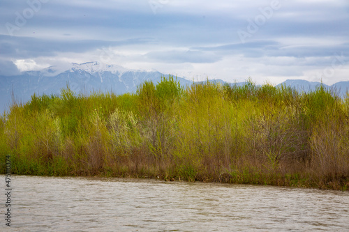 Beautiful daylight scenery of snowy Caucasus mountains with a wavy lake in front and modern buildings in the middle photo