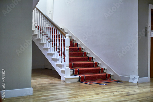 Fototapeta interior stairs with red carpet, balusters and wooden handrails