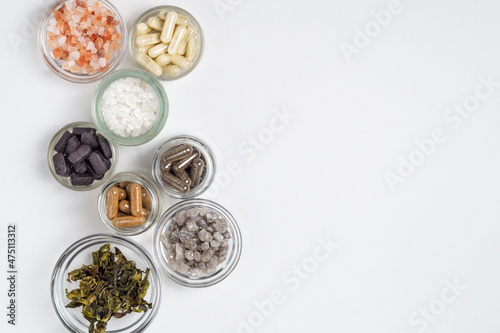 Dietary supplements in capsules, white, gray, pink crystals of sea salt and algae