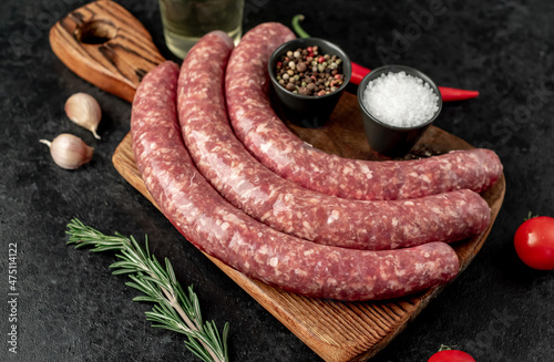 raw sausages for grilling on a stone background