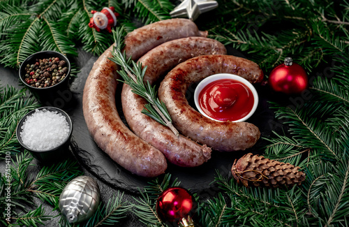 christmas grilled sausages with spruce and christmas toys on stone background