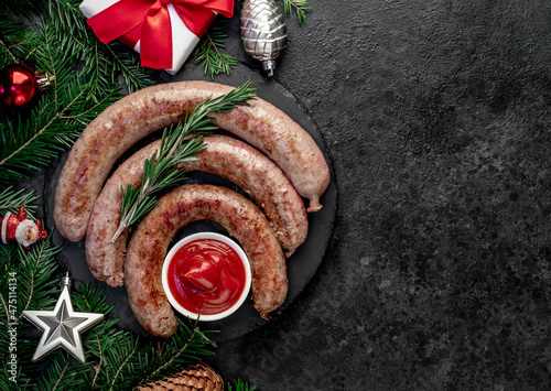 christmas grilled sausages with spruce and christmas toys on stone background with copy space for your text