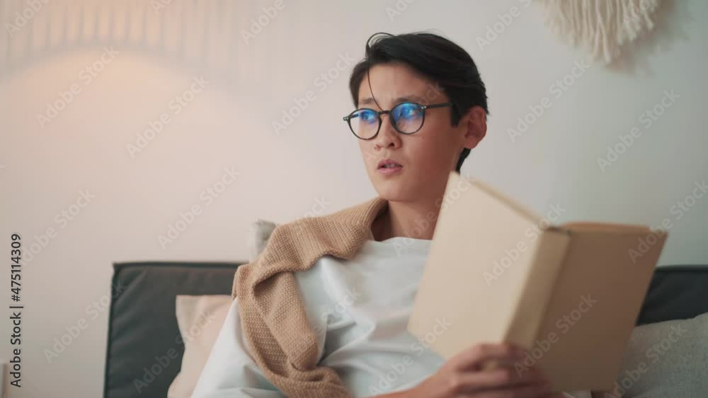 Concentrated Asian man reading book at home Concentrated Asian man reading book at home