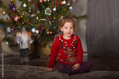 Little girl child in red Christmas sweater for New Year at home... © Nelly