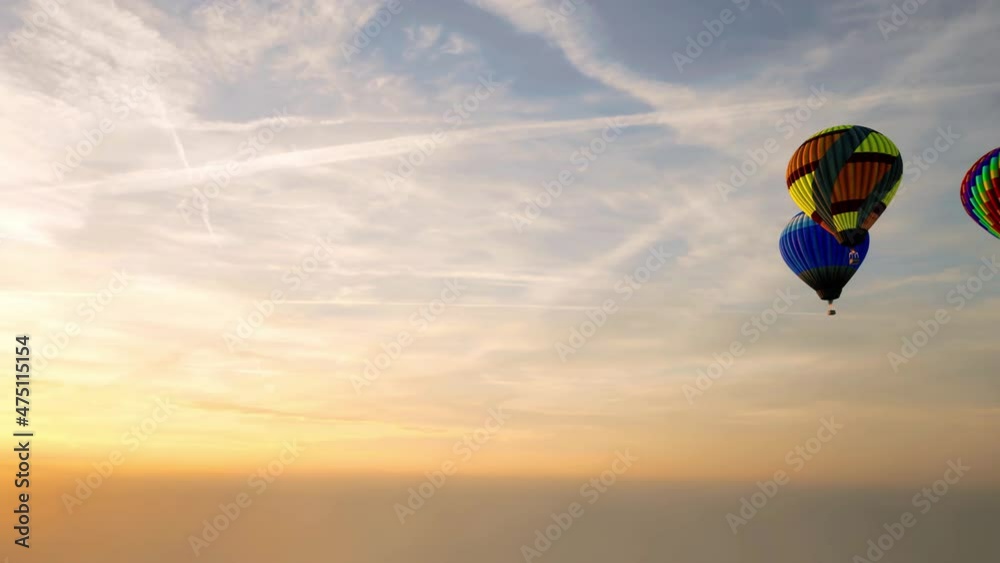 Multiple hot air balloons racing across the sky at sunset.