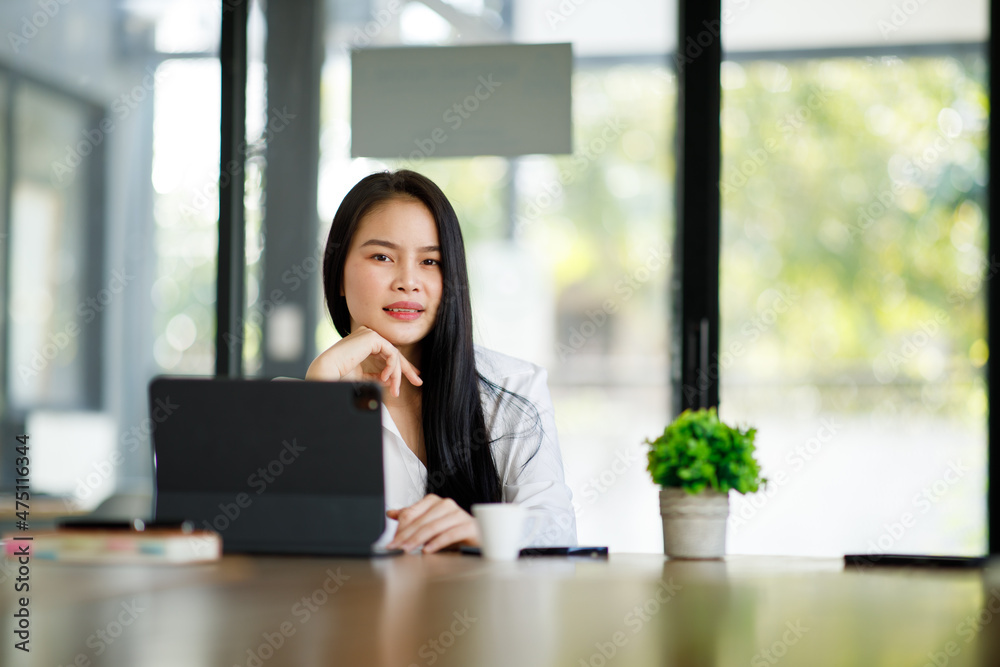 Portrait of Young Asian woman hand freelancer is working her job on computer tablet in modern office. Doing accounting analysis report real estate investment data, Financial and tax systems concept. Portrait of Young Asian woman hand freelancer is working her job on computer tablet in modern office. Doing accounting analysis report real estate investment data, Financial and tax systems concept.