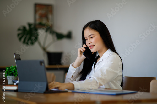 Portrait of Young Asian woman hand freelancer is working her job on computer tablet in modern office. Doing accounting analysis report real estate investment data, Financial and tax systems concept.