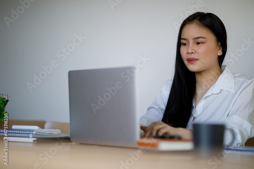 Portrait of Young Asian woman hand freelancer is working her job on computer tablet in modern office. Doing accounting analysis report real estate investment data, Financial and tax systems concept.