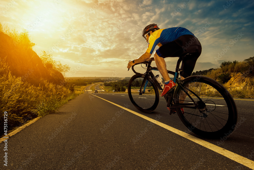 Asian man riding a bicycle on an open road. foto de Stock | Adobe Stock