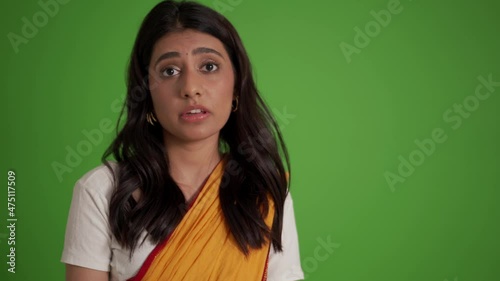 Handsome traditional Indian woman giving positive answer in the green studio photo